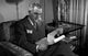 Man Reading Report in Chair Poster Print - A thoughtful image perfect for home or office decor.