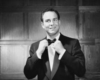 Close-up poster print of a mid-adult man adjusting a bow tie and smiling.