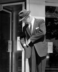 Man Looking Into Pocket Outside Store Poster Print, available in multiple sizes.