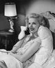 Side profile of a young woman talking on the telephone while lying in bed poster print.
