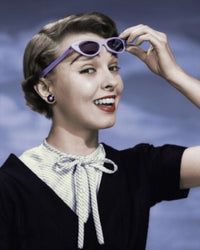 Close-up poster print of a young woman holding sunglasses.