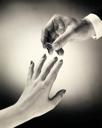 Close-up of a man's hand placing a ring on a woman's finger poster print.