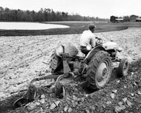Rear view of a farmer plowing a field with a tractor poster print.