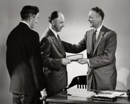 Side profile of a businessman presenting a gift in a professional setting.