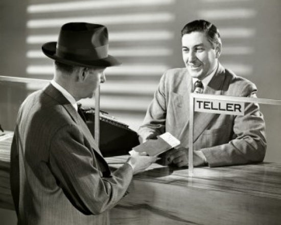 Mature man handing a bank book to a bank teller poster print