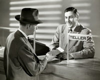 Mature man handing a bank book to a bank teller poster print