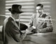Mature man handing a bank book to a bank teller poster print