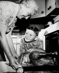 Thanksgiving poster print of grandmother taking turkey from oven with grandson watching