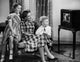 Poster print of a mid-adult woman with her son and daughter watching television.