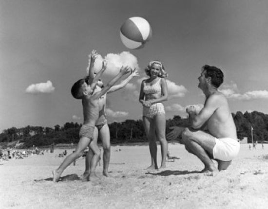 Parents playing with two children on the beach poster print.