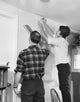Mid adult couple applying wallpaper in a bright room poster print