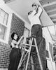 Low angle view poster print of a man and woman fixing plywood on a porch.