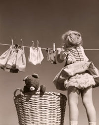 Poster print of a girl hanging clothes on a clothes line, capturing a nostalgic scene.