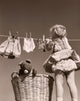 Poster print of a girl hanging clothes on a clothes line, capturing a nostalgic scene.