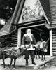 Santa Claus standing with two reindeer in front of a building poster print
