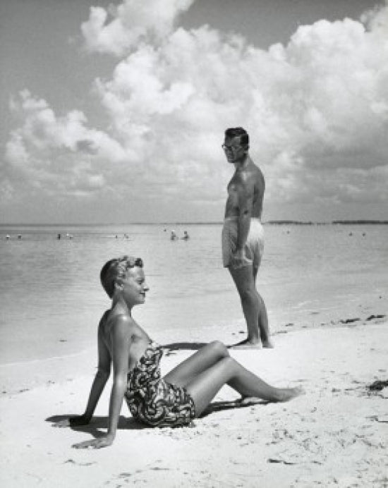 Side profile of a young woman sitting with a young man on the beach poster print.