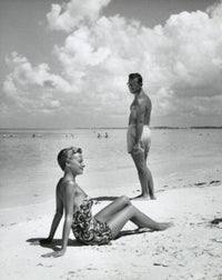 Side profile of a young woman sitting with a young man on the beach poster print.