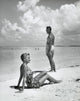 Side profile of a young woman sitting with a young man on the beach poster print.