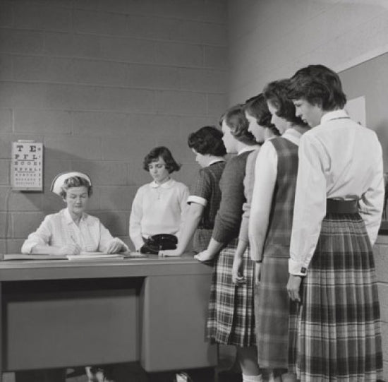 Teenage girls standing beside a nurse's desk poster print.