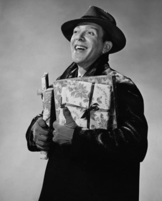 Close-up of a mid adult man smiling and holding Christmas presents.