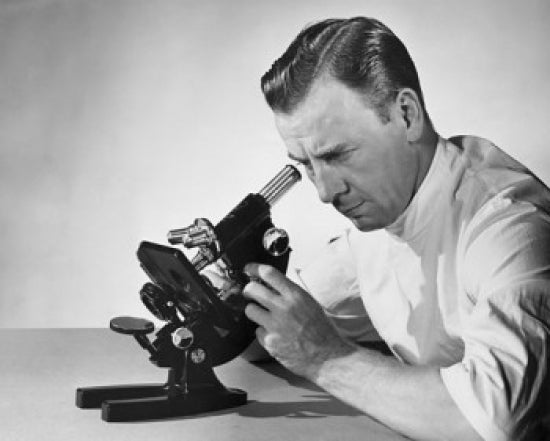 Male researcher looking through a microscope poster print.