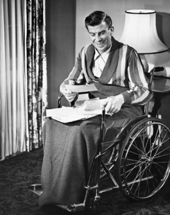 Mature man sitting in a wheelchair reading documents poster print.
