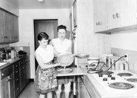 Teenage girl cooking in the kitchen with mother beside her poster print