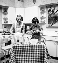 Poster print of two teenage girls preparing food in the kitchen.