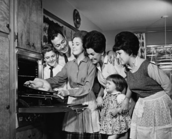 Teenage girl putting a turkey into an oven poster print