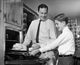Father and son putting turkey into an oven poster print.