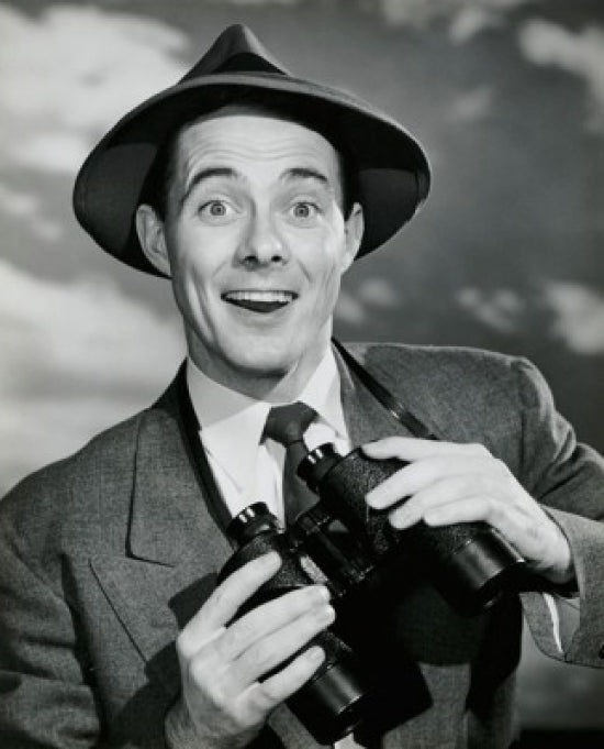 Portrait of a young man smiling while holding binoculars poster print