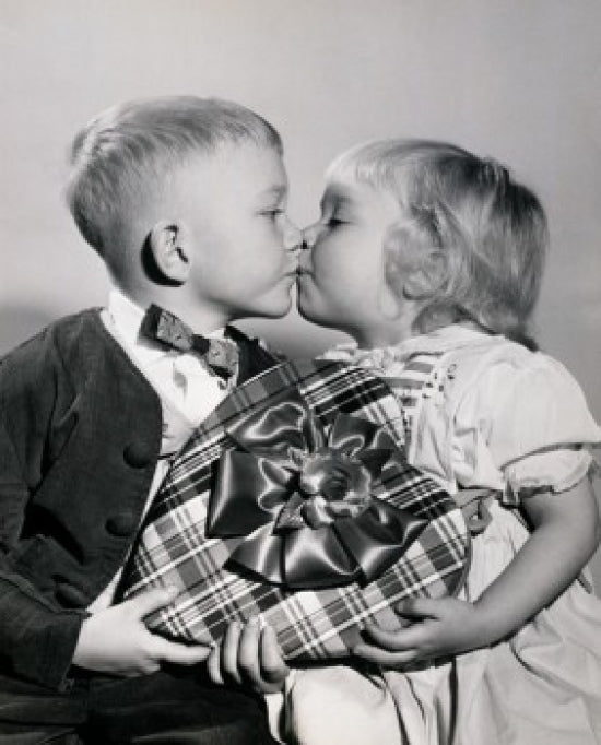 Close-up of a boy and girl kissing while holding a Valentine gift poster print.