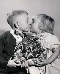 Close-up of a boy and girl kissing while holding a Valentine gift poster print.