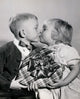 Close-up of a boy and girl kissing while holding a Valentine gift poster print.