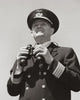 Poster print of a ship captain holding binoculars from a low angle view.