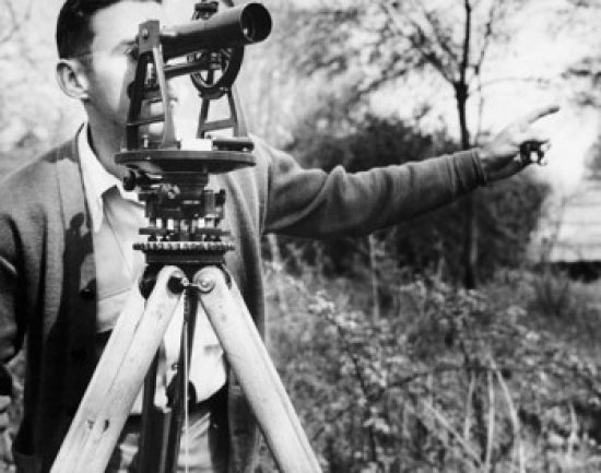 Male surveyor looking through a theodolite poster print