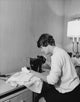 Mid adult woman sewing with a sewing machine poster print.