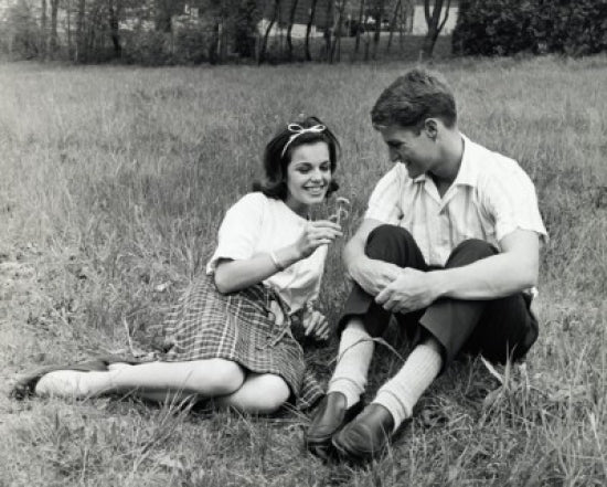 Young couple sitting in a park smiling poster print