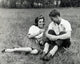 Young couple sitting in a park smiling poster print