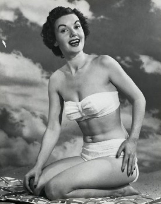 Portrait of a young woman kneeling on the beach smiling poster print.