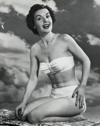 Portrait of a young woman kneeling on the beach smiling poster print.