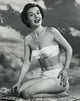 Portrait of a young woman kneeling on the beach smiling poster print.
