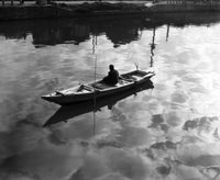 High angle view of a man fishing from a rowboat on a lake poster print.