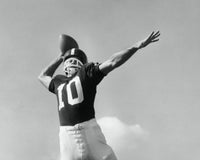 Football player throwing a football poster print in dynamic low angle view.