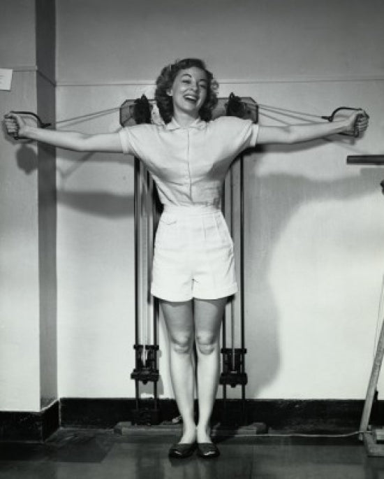 Young woman smiling while exercising in a gym poster print.