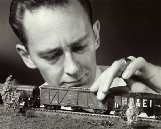 Close-up of a mid adult man holding a model of a toy train.