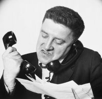 Close-up poster print of a frustrated businessman using two telephones.