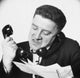Close-up poster print of a frustrated businessman using two telephones.