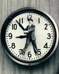 Close-up of a man walking in front of a clock poster print.