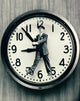 Close-up of a man walking in front of a clock poster print.